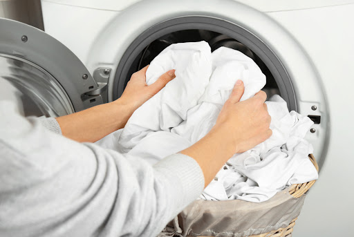 Female hands getting out clean clothes from washing machine