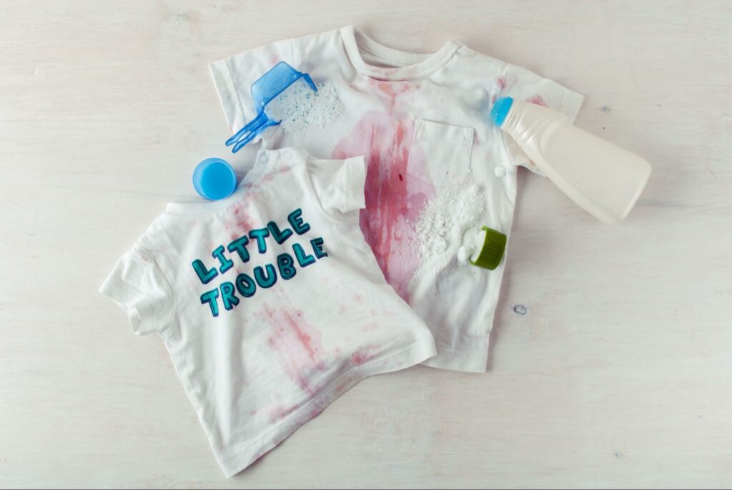 Stained children's shirts, one says "little trouble"