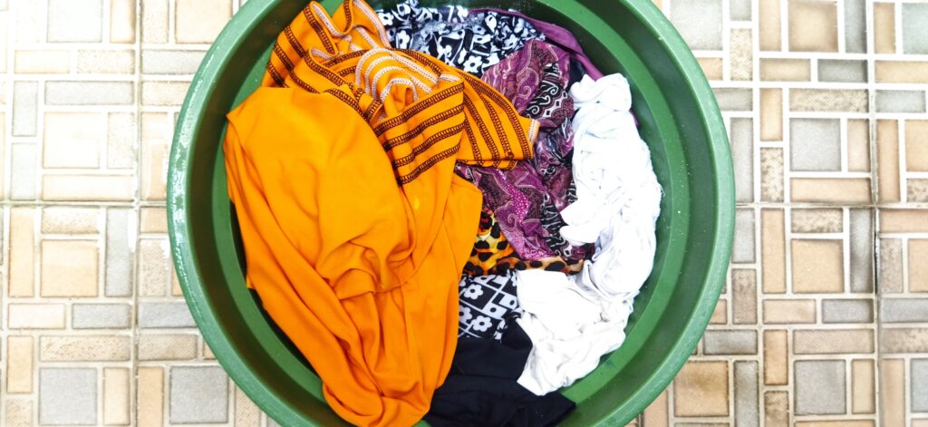 A pile of clothes in a green laundry basket.